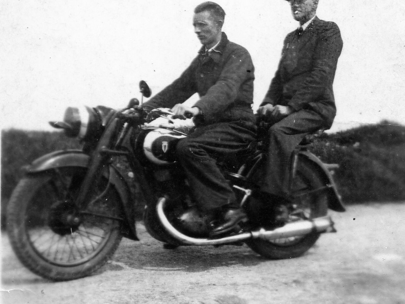 Twee mannen rijden op een motorfiets.