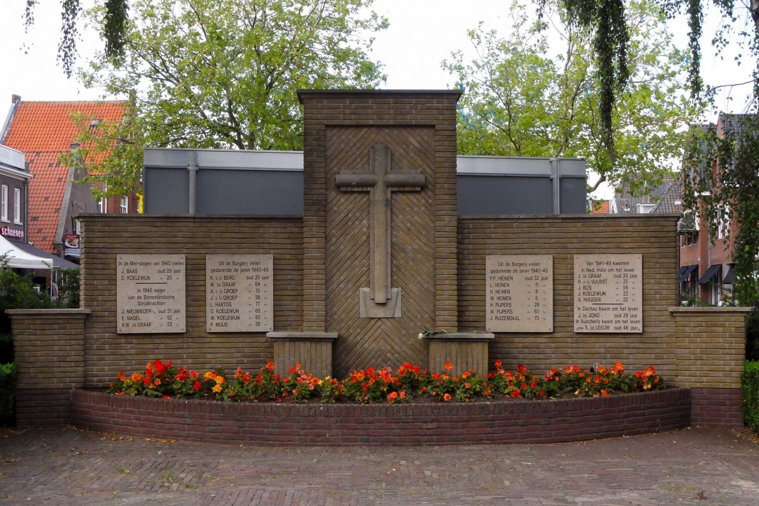 Gedenkmuur met kruis en vier plaquettes met namen van gevallenen